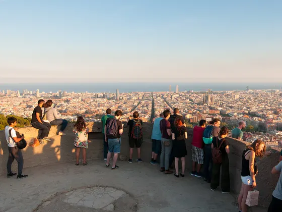 Gente de pie en el borde de los Bunkers del Carmel mirando la ciudad, que se extiende hasta el mar, a última hora de la tarde.
