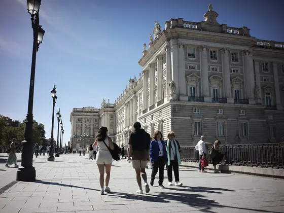 La fachada este del Palacio Real desde la explanada, con las farolas de la plaza de Oriente a la izquierda y gente paseando delante.